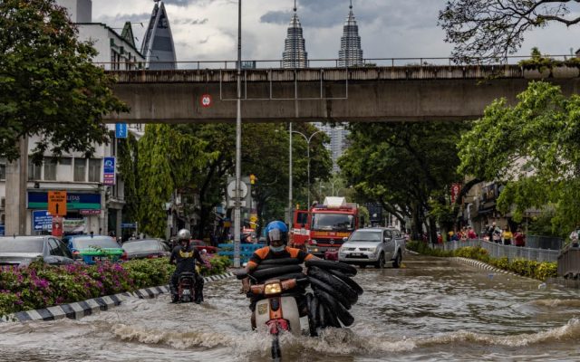 क्वालालम्पुरको जलमग्न सडकमा मोटरसाइकल यात्री