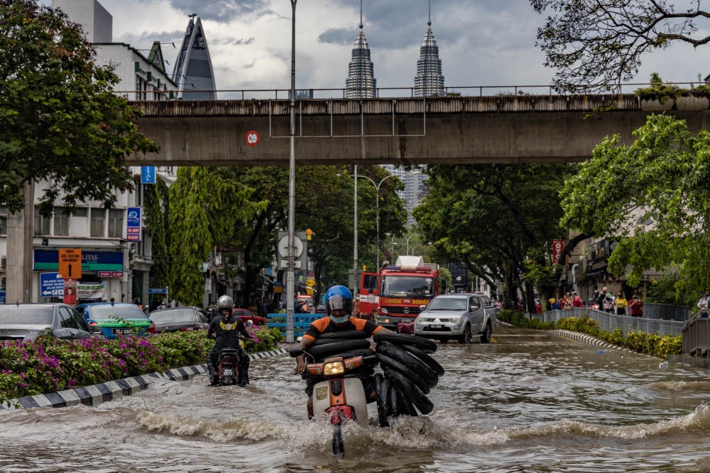 क्वालालम्पुरको जलमग्न सडकमा मोटरसाइकल यात्री